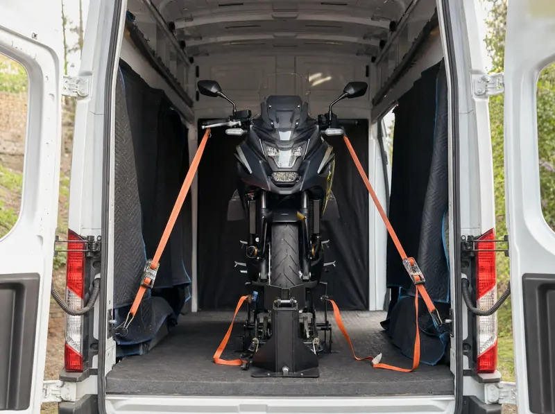 Motocykl w kołysce transportowej, zapięty pasami w busie